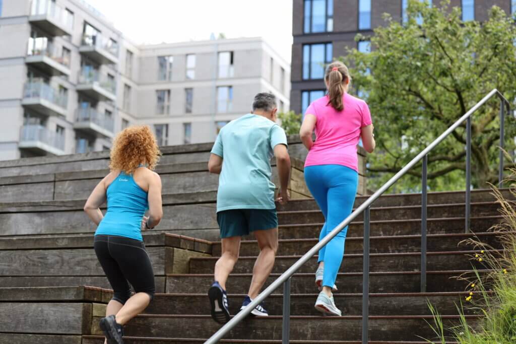 Ein Mann und zwei Frauen von hinten laufen eine Treppe hoch