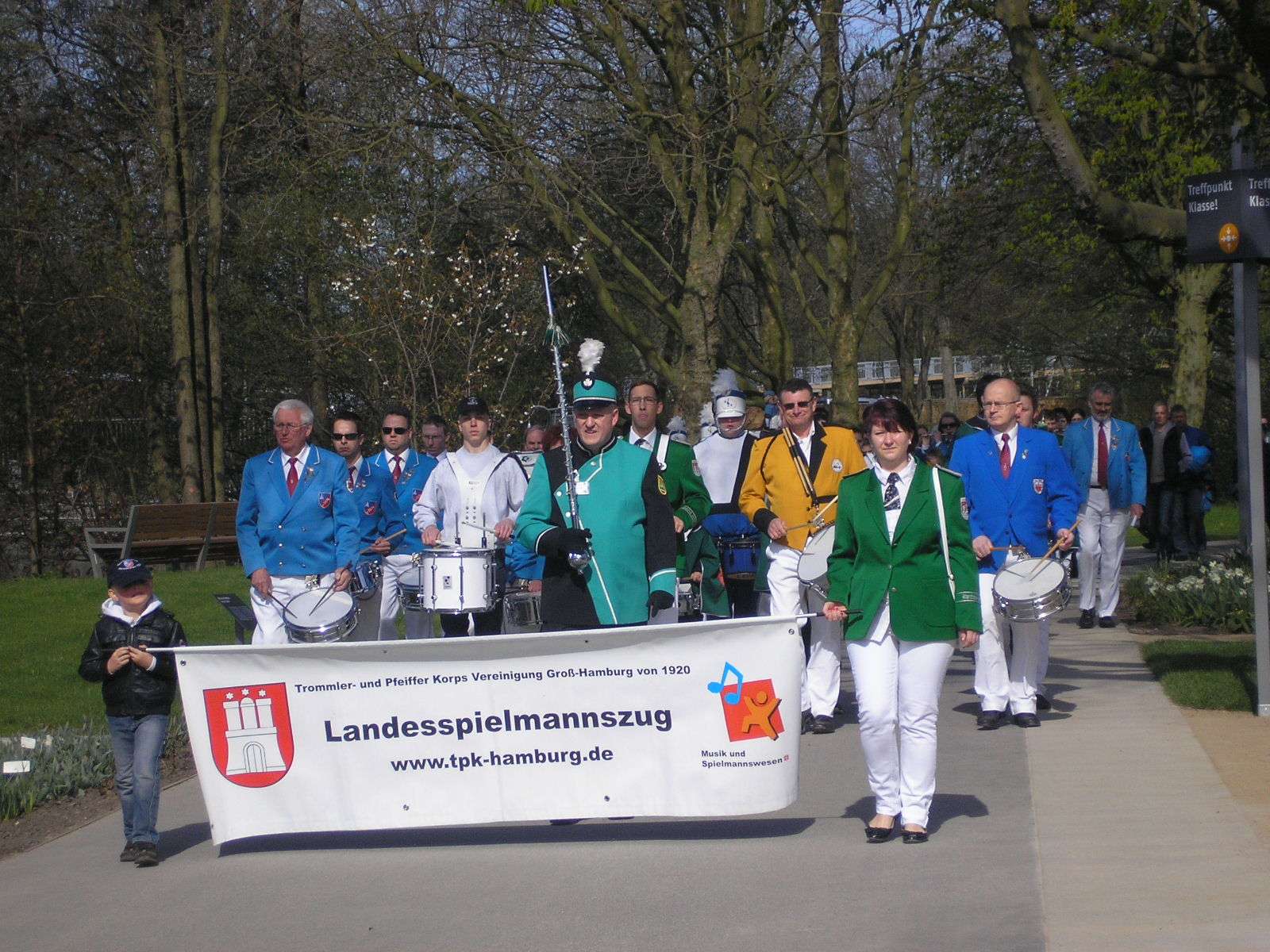 Landesspielmannszug Hamburg marschiert mit einem Banner, das vorweg getragen wird
