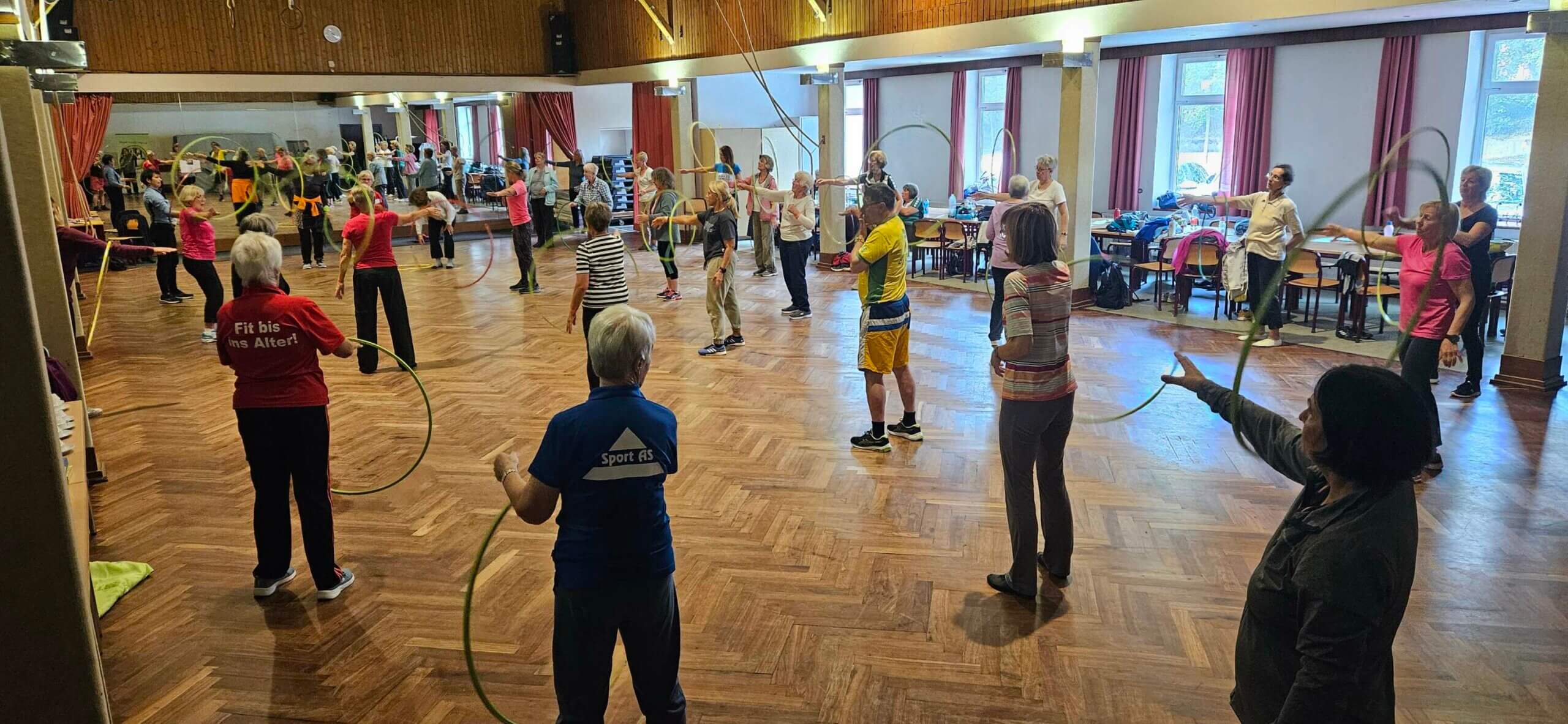 Workshop-Einheit beim Neugrabenr Event mit dem Reifen. Teilnehmenden stehen im Raum verteilt und halten den Gymnastikreifen vor sich.