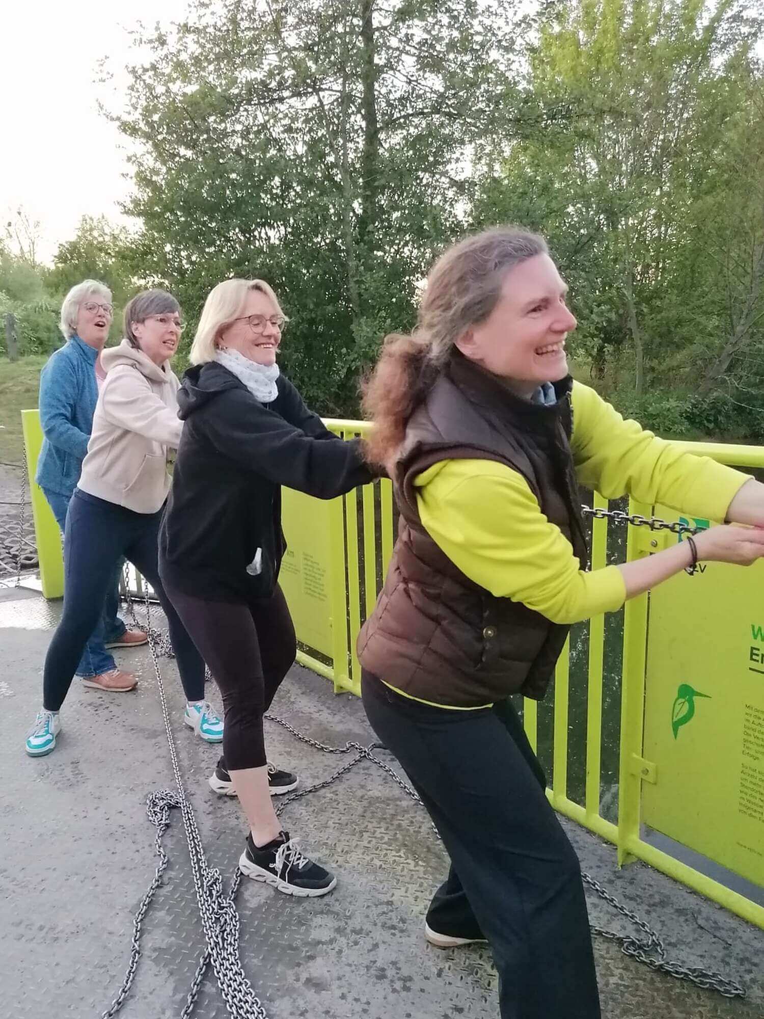 Menschen ziehen in Sportkleidung an einem Strang an einem Brückengeländer