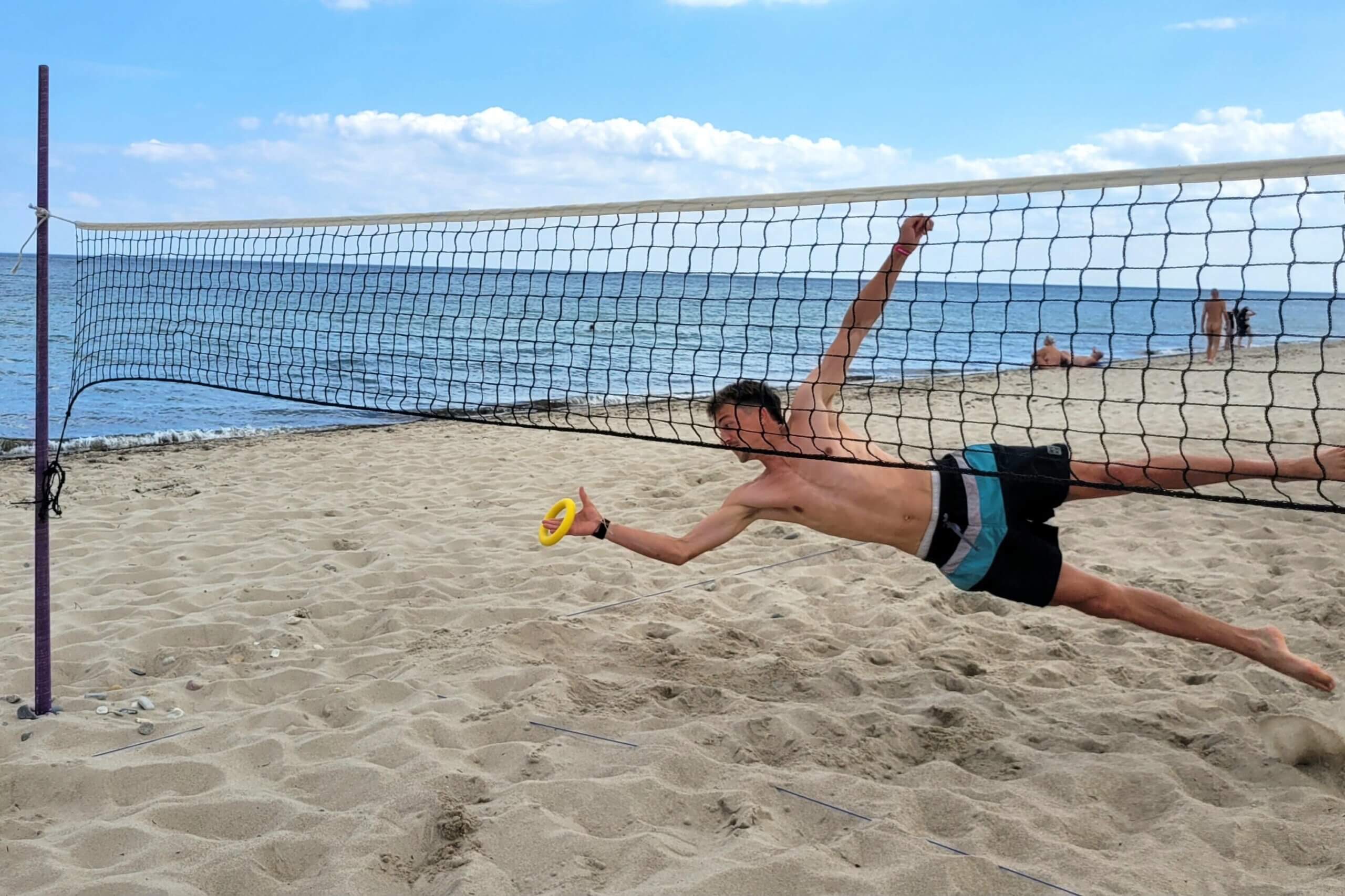 Ein Spieler springt seitlich zum Netz und fängt den Ring.
