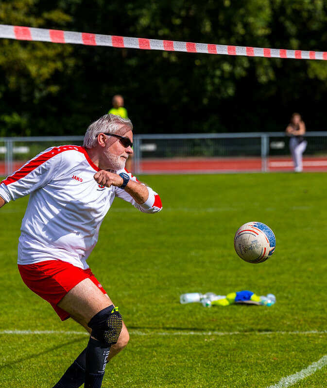 Älterer Spieler mit Sonnenbrille, vom Walddörfer SV schlägt nach dem Faustball.