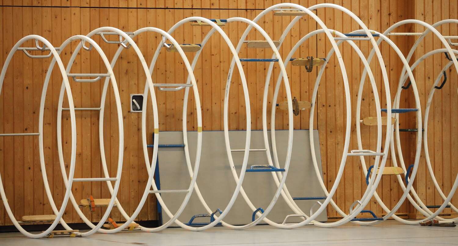 mehrere Rhönräder verschiedener Größen stehen in einer Reihe nebeneinander in einer Turnhalle