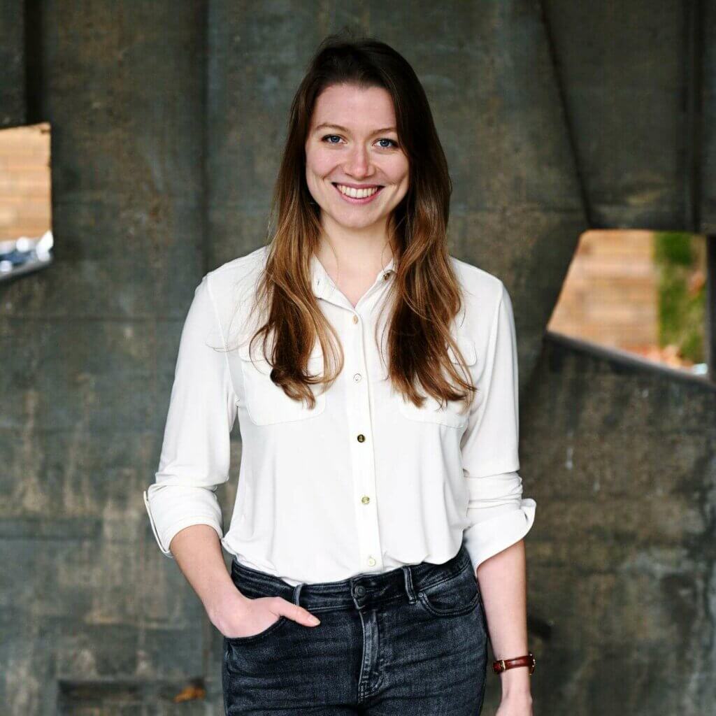 Elena Breyer lächelnd vor einem grauen Hintergrund