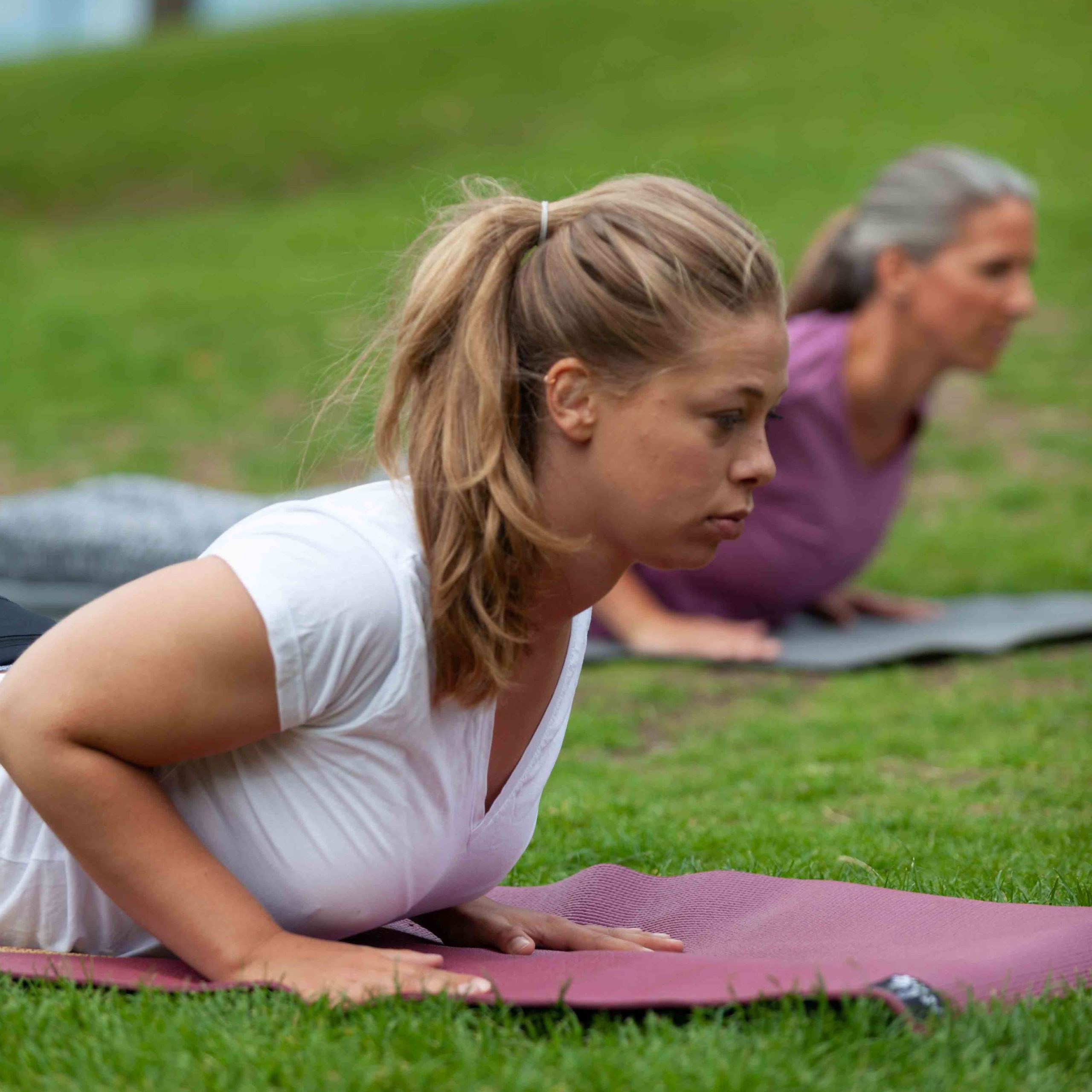 Frau liegt auf einer Yoga-Matte und praktiziert die "Kobra"