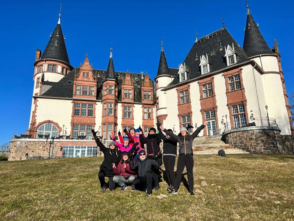 Frauengruppe im Winter mit wolkenlosem Himmel vor dem Seehotel Schloss Klink