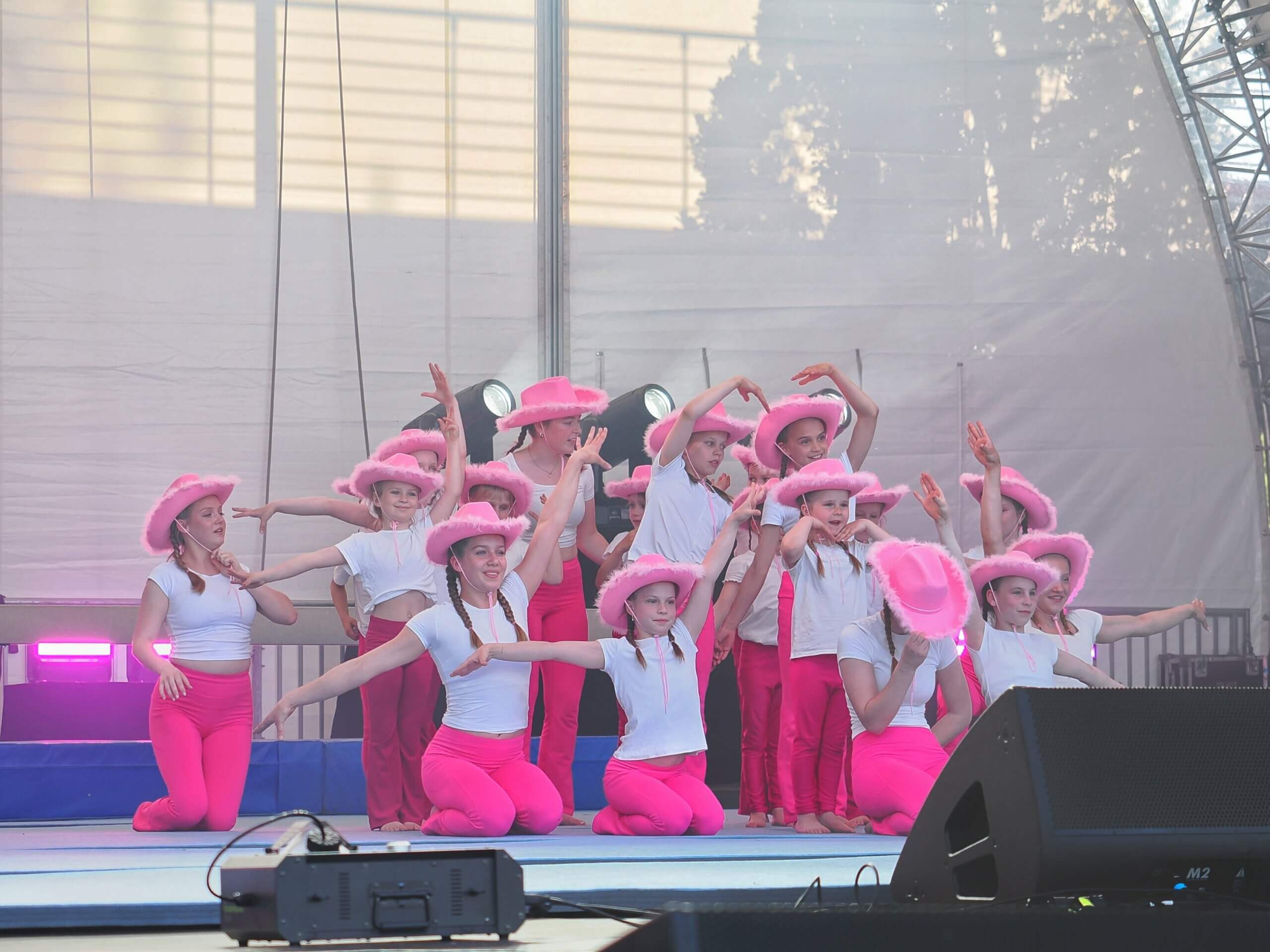 Gruppe junger Mädchen in rosa Cowboyhüten und weißen T-Shirts in Formation auf Knien