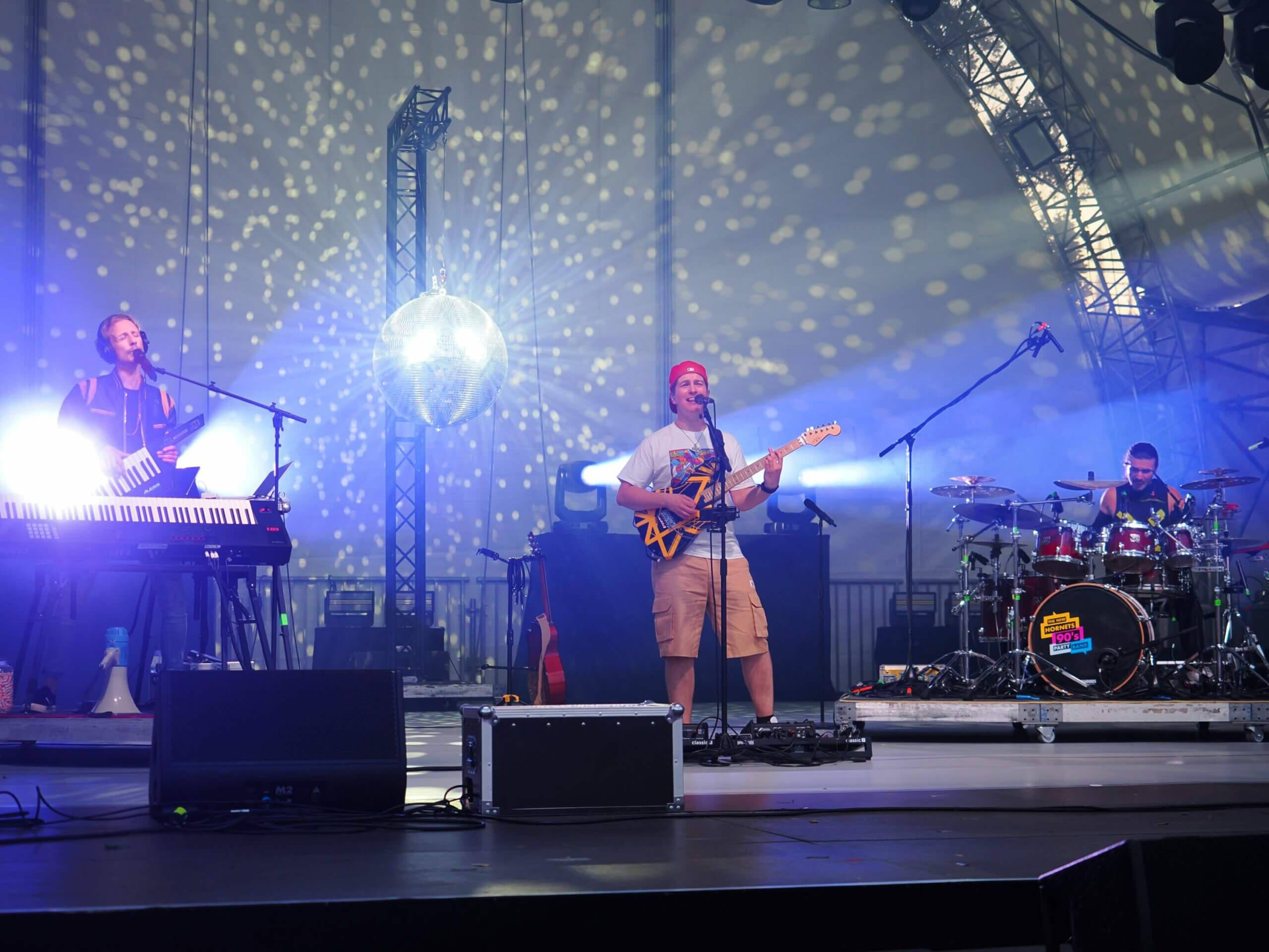 Band auf Bühne mit blauem Licht und Diskokugel im HIntergrund