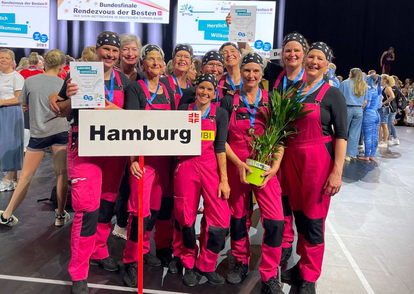 Showgruppe Jakaduwo in roten Arbeitslatzhosen und einem "Hamburg"-Schild beim Rendezvous der Besten