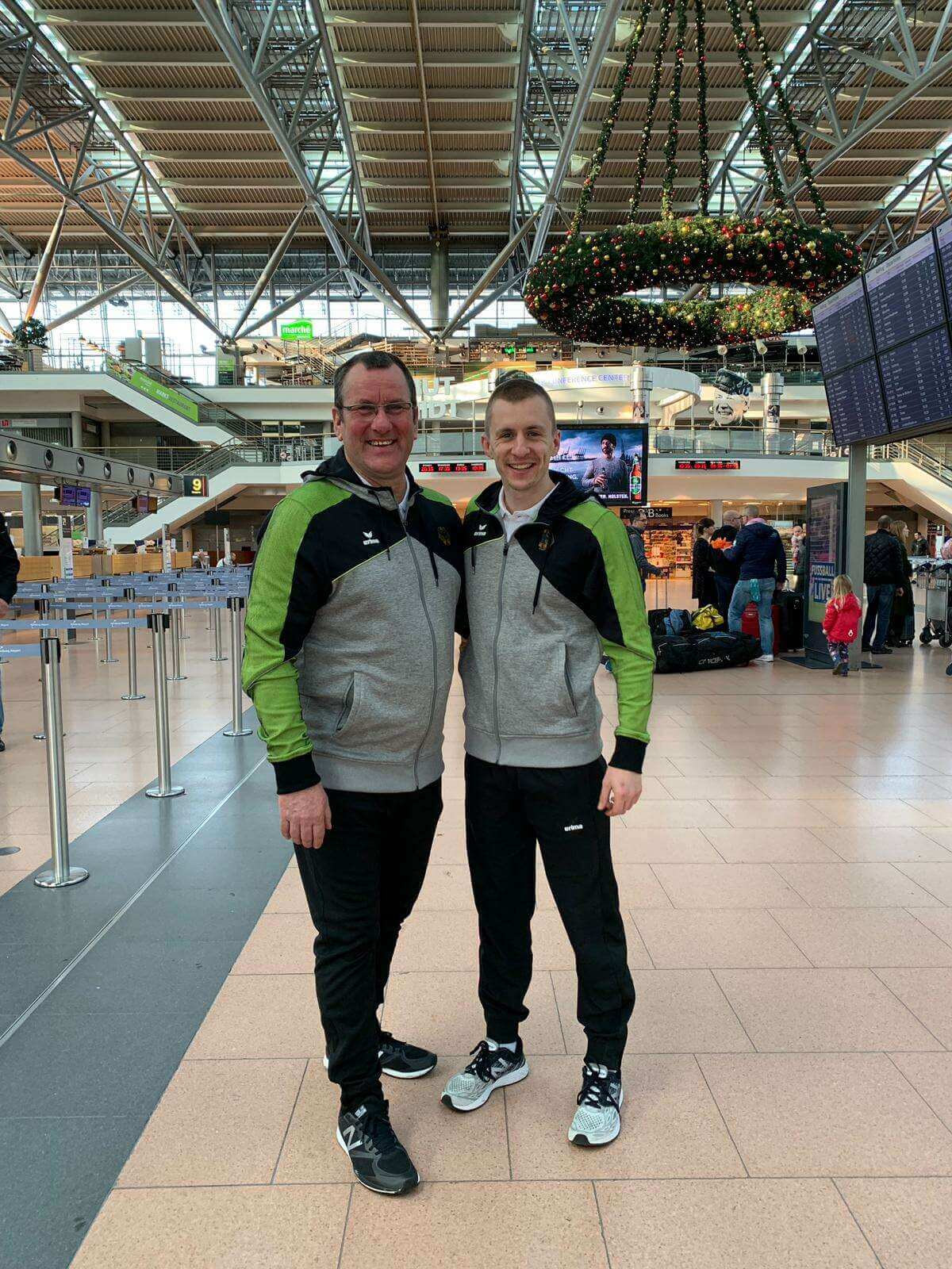 Olaf Schmidt und sein Sohn Daniel Schmidt in Trainingsanzügen vor dem Abflug am Flughafen zur Trampolin WM nach Tokio 2021