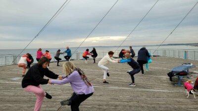 Gruppe macht Yogaübung auf einem Steg