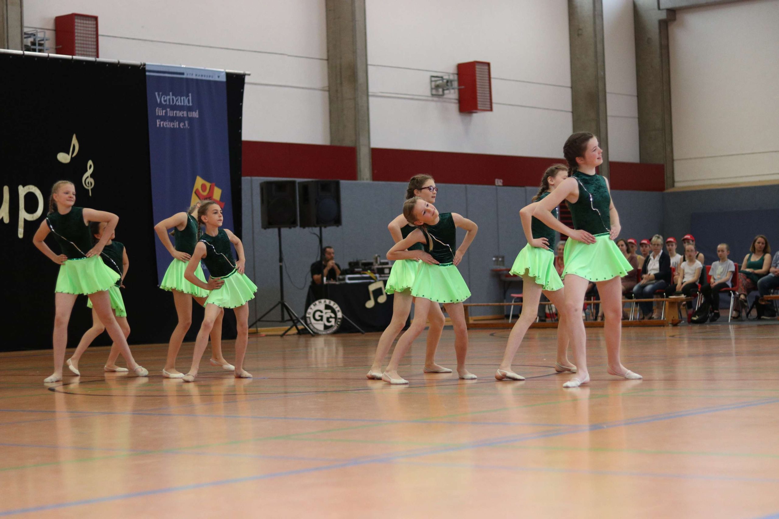 Gruppe aus Tänzerinnen mit einem dunkelgrünen Oberteil und einem leuchtenden hellgrünen Rock bei ihrer Performance