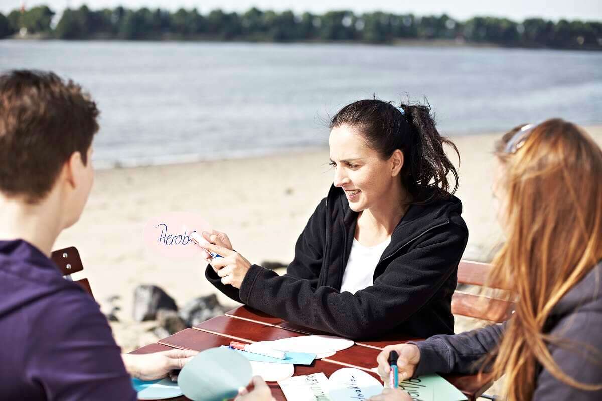Junge Menschen lernen mit Freude gemeinsam am Strand