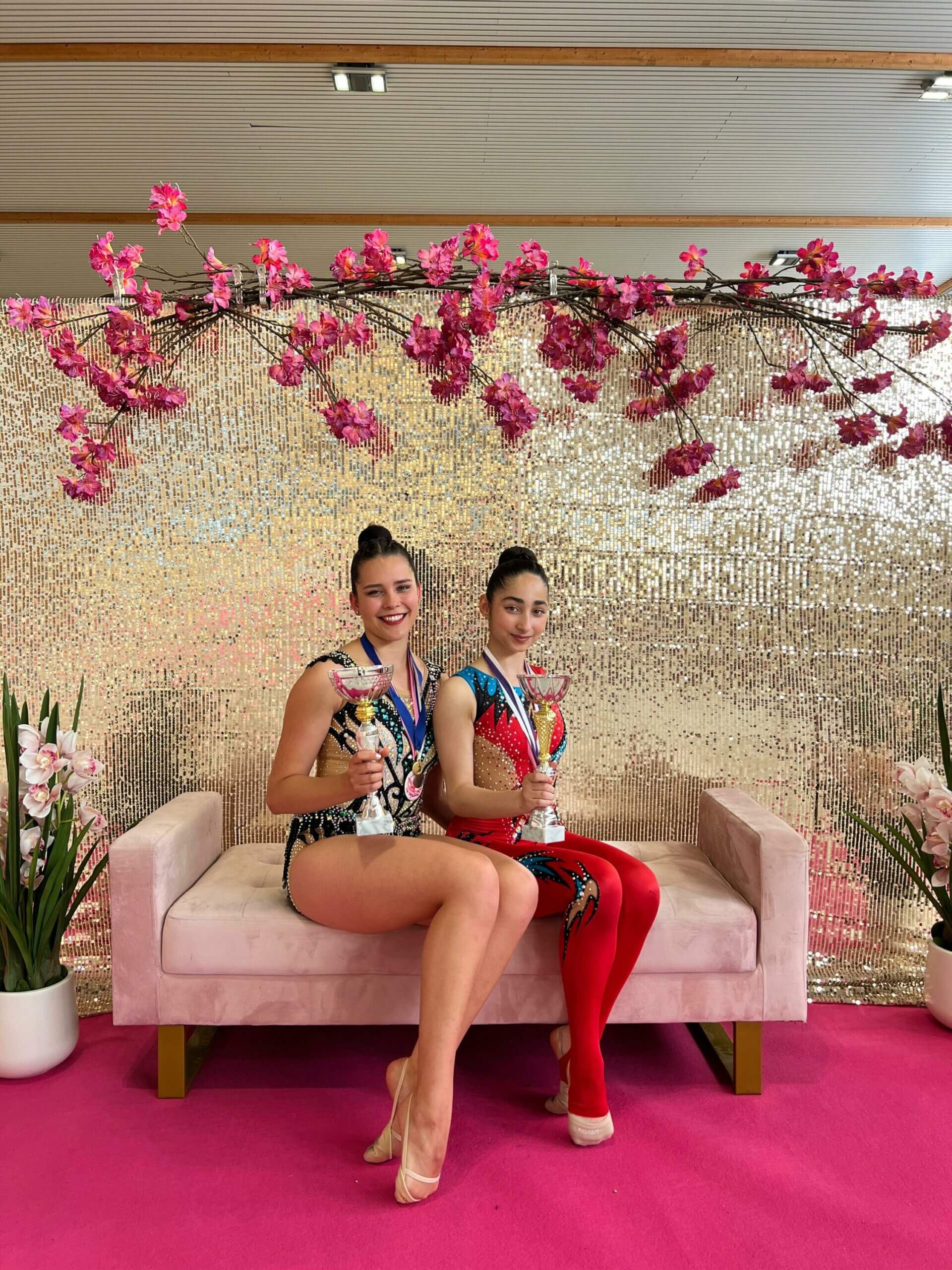 Zwei Gymnastinne sitzen mit ihren Pokalen auf einem Sofa beim Arnumer Cup in Hannover.