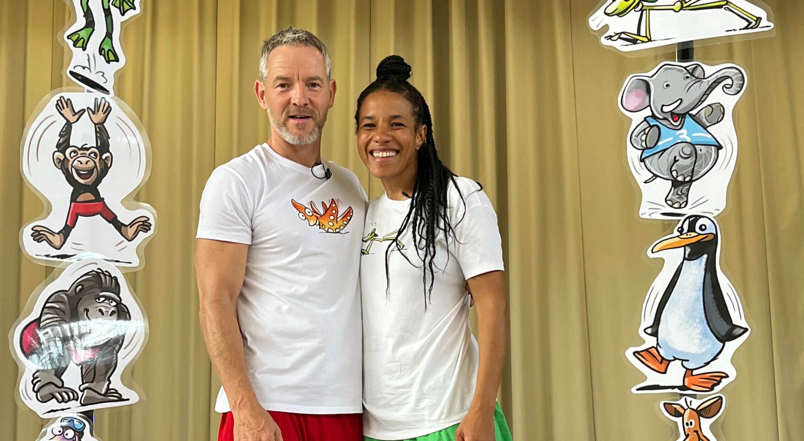 Phil und Sarah stehen in einem Bogen lustiger bunter Tierbilder