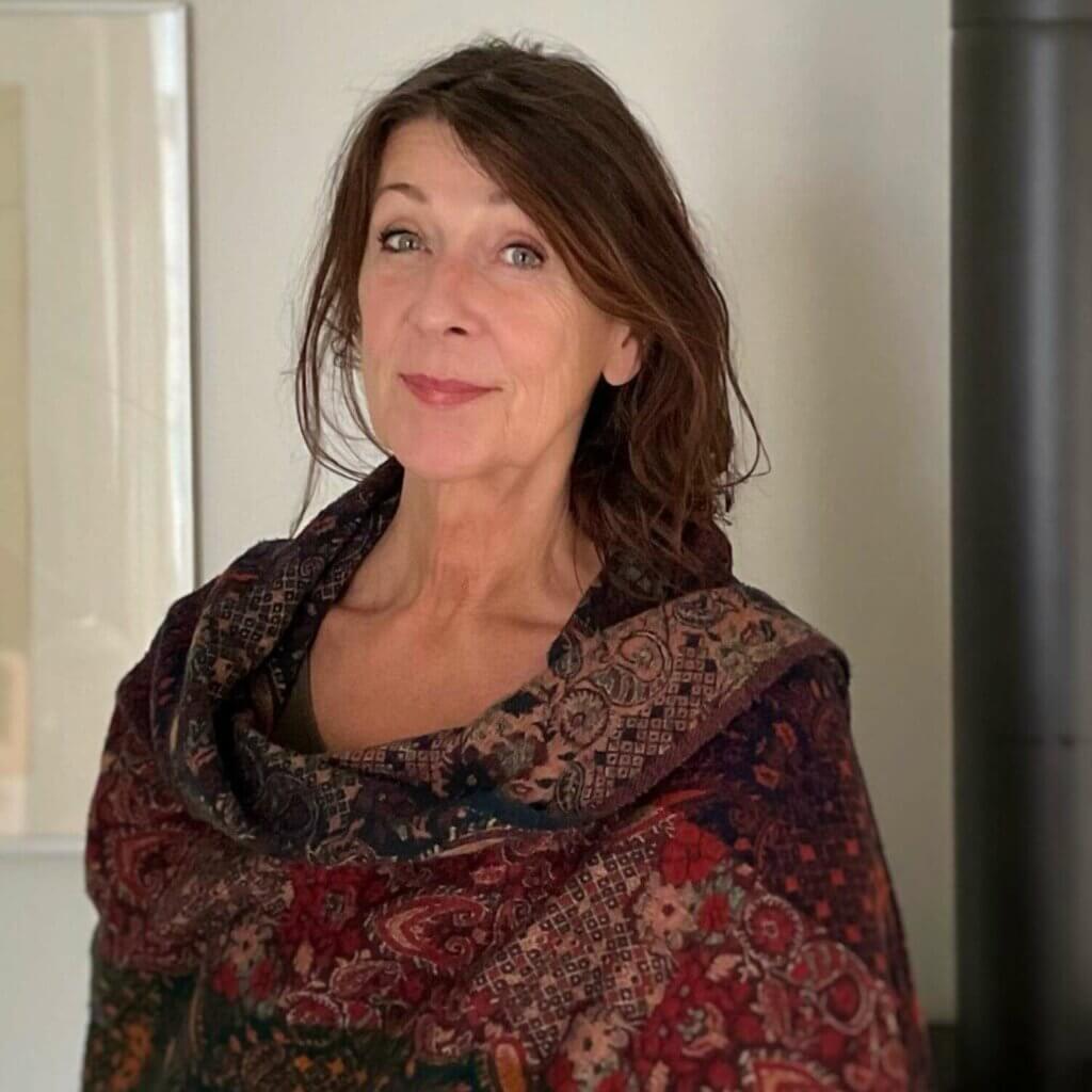 In einem Sportraum mit einem Spiegel ist eine Gruppe von Menschen beim Qigong zu sehen. Alle strecken den rechten Arm diagonal nach links oben aus und neigen den Oberkörper leicht nach links