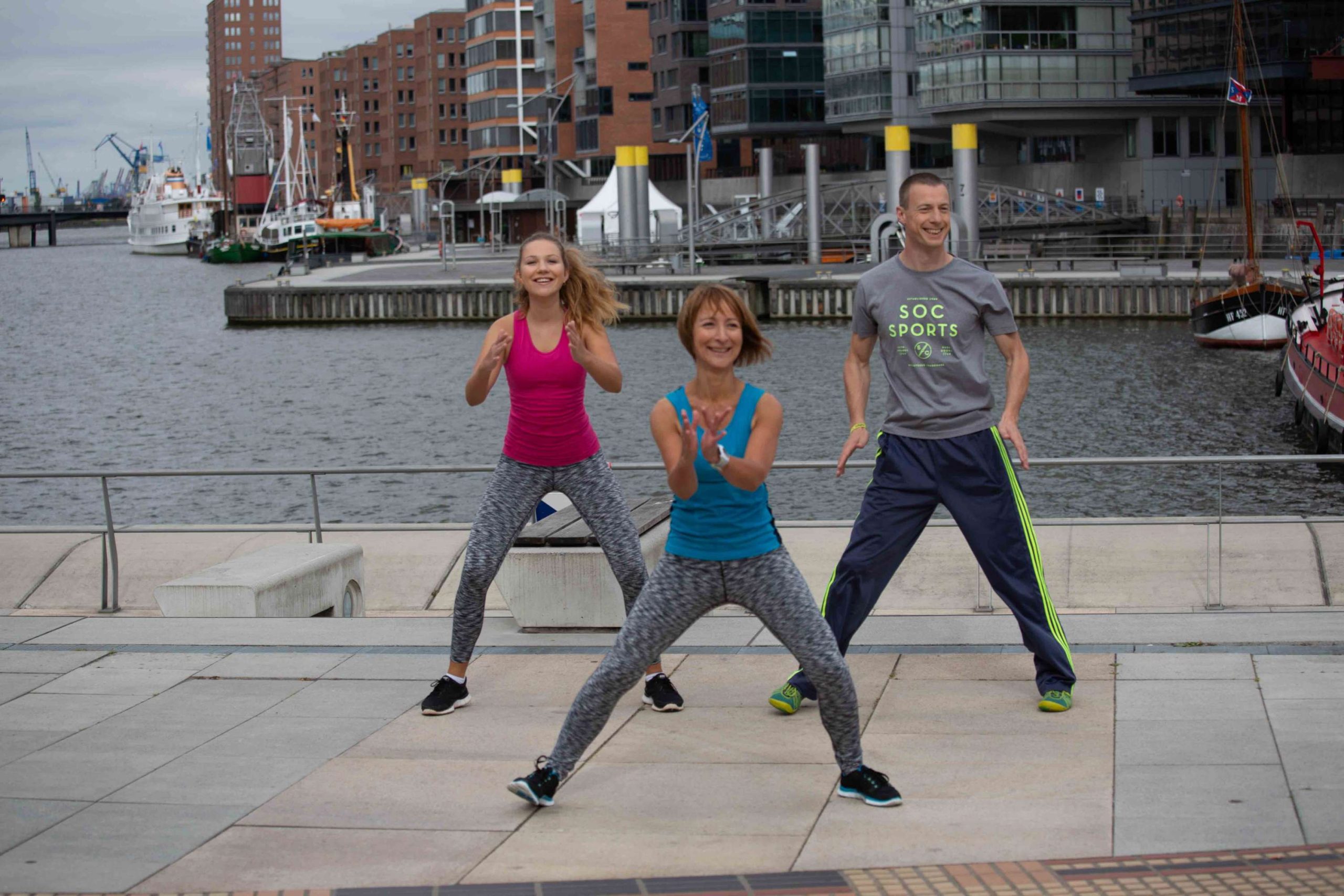 Drei Fitness-Sportler*innen beim Side-Step in der Hafencity Hamburg