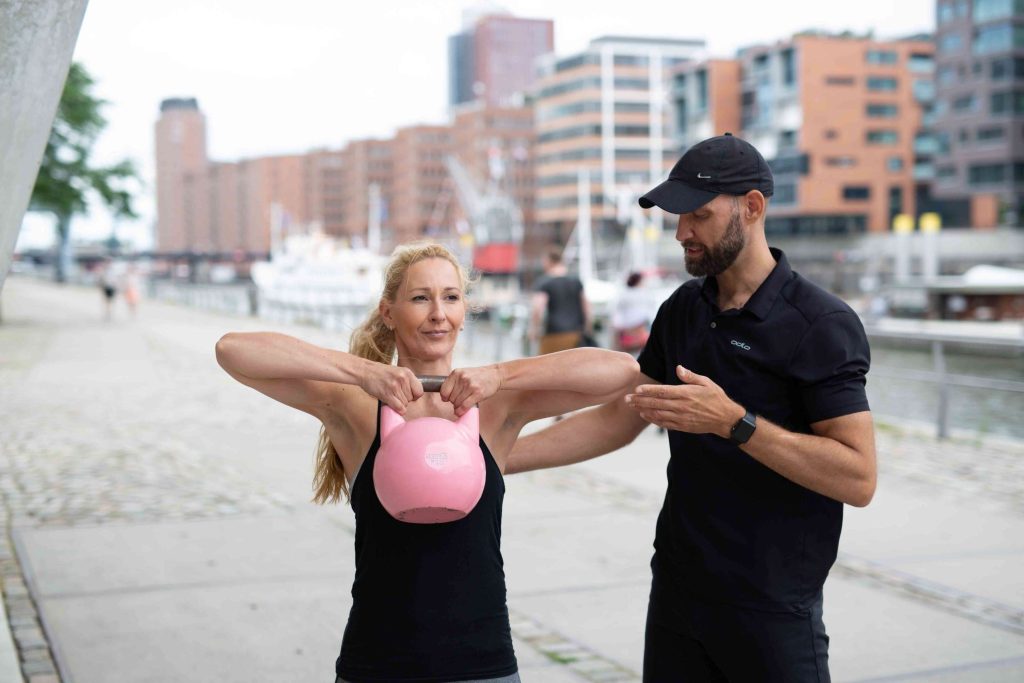 Personaltrainer erklärt seiner Fitnesssportlerin eine Übung mit der Kettlebell