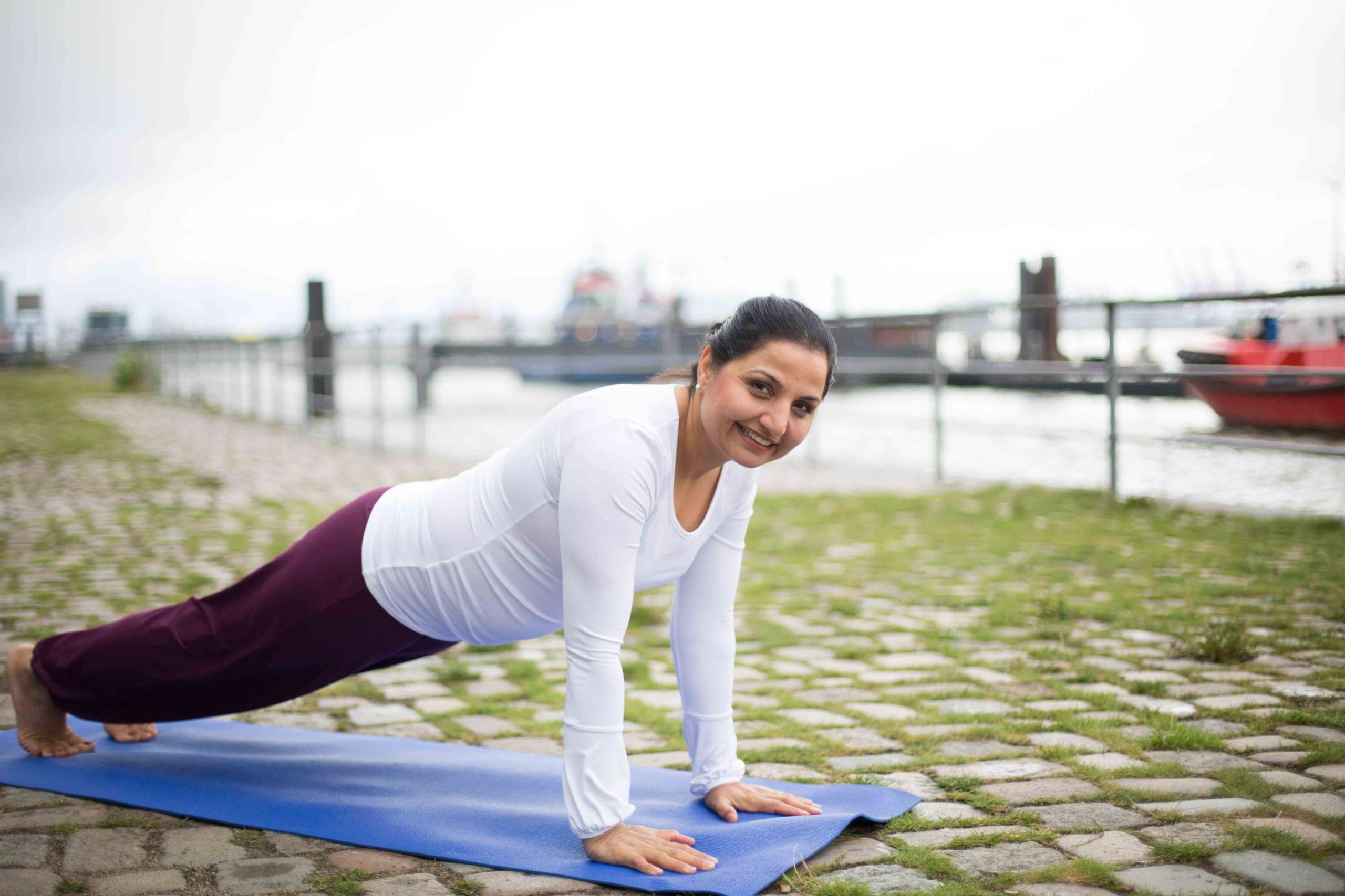 Frau, die eine Yoga-Übung am Hafen macht