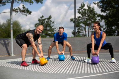 Drei Fitness-Sportler*innen bereiten sich auf Übungen mit dem Kettlebell vor