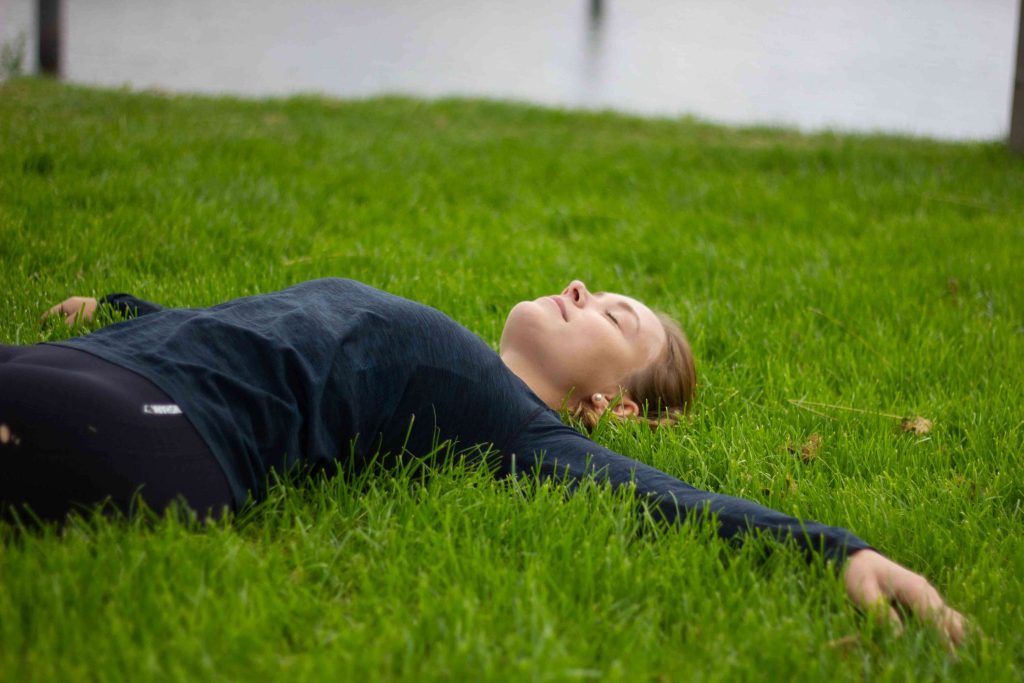 Frau liegt im Gras mit geschlossenen Augen