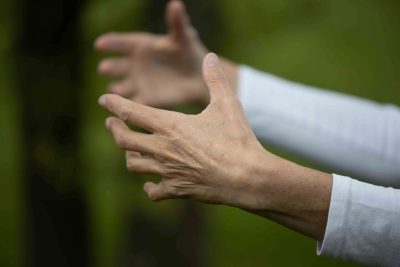 Qigong: umarmende Hände vor unscharfem Hintergrund