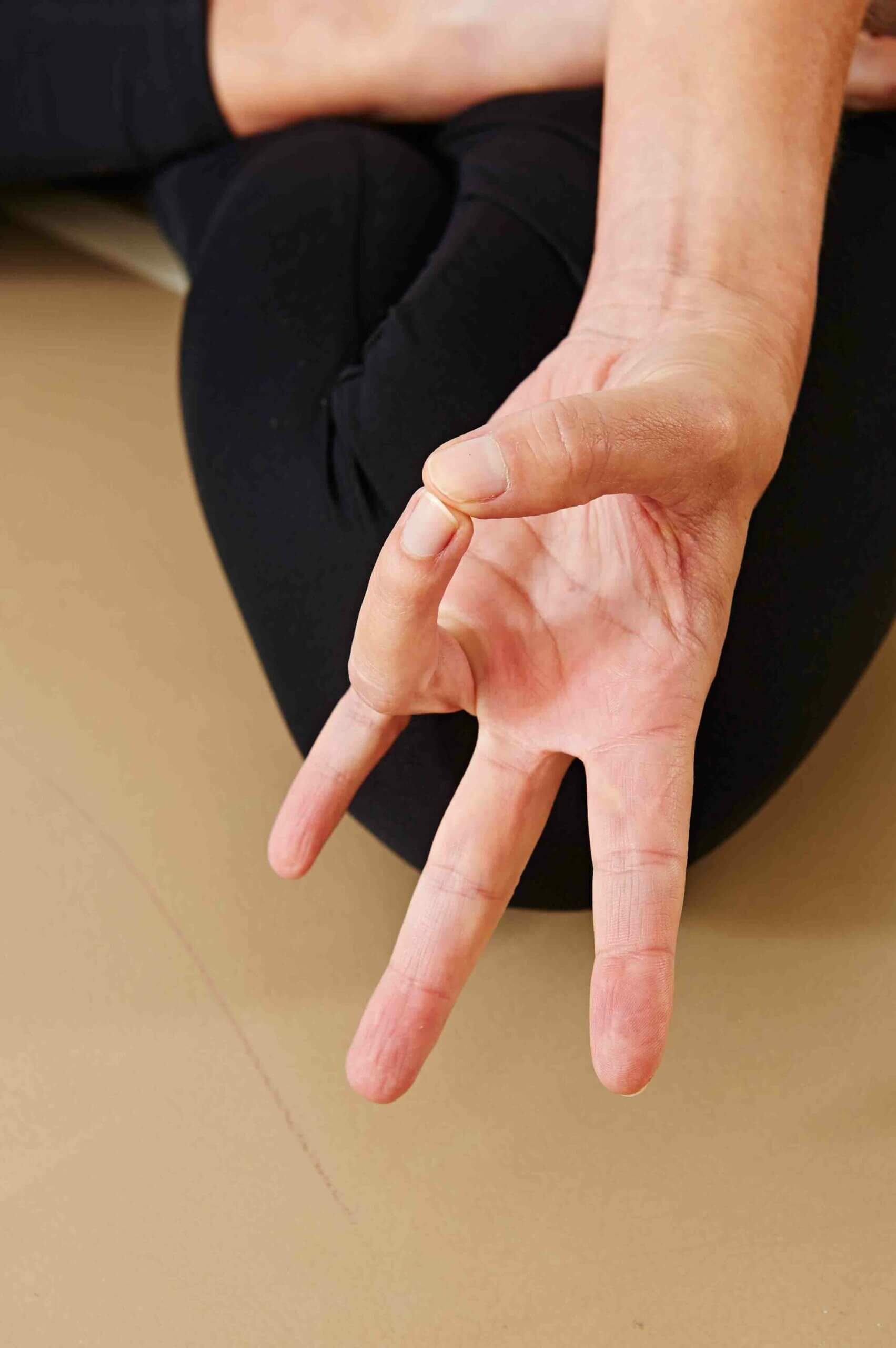 Eine Hand ist zu sehen, die mit Daumen und Mittelfinger, die sich beführen ein Mudra bildet.